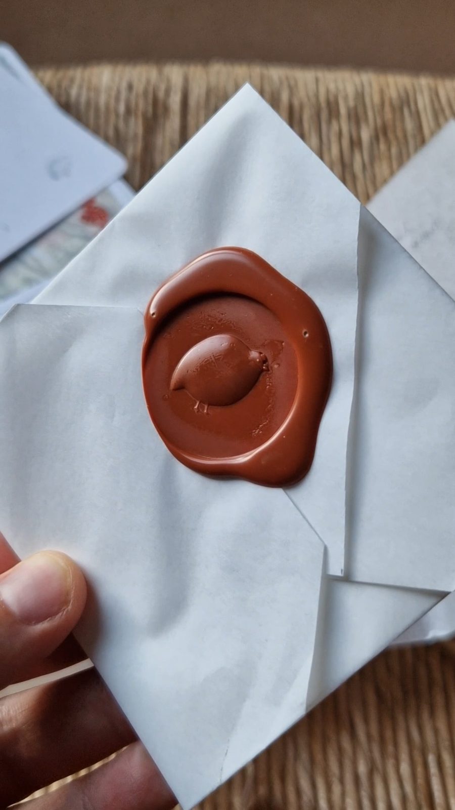 Enveloppe du coffret I — Le goût tenue en main, scellée d’un sceau de cire terracotta frappé d’une caille