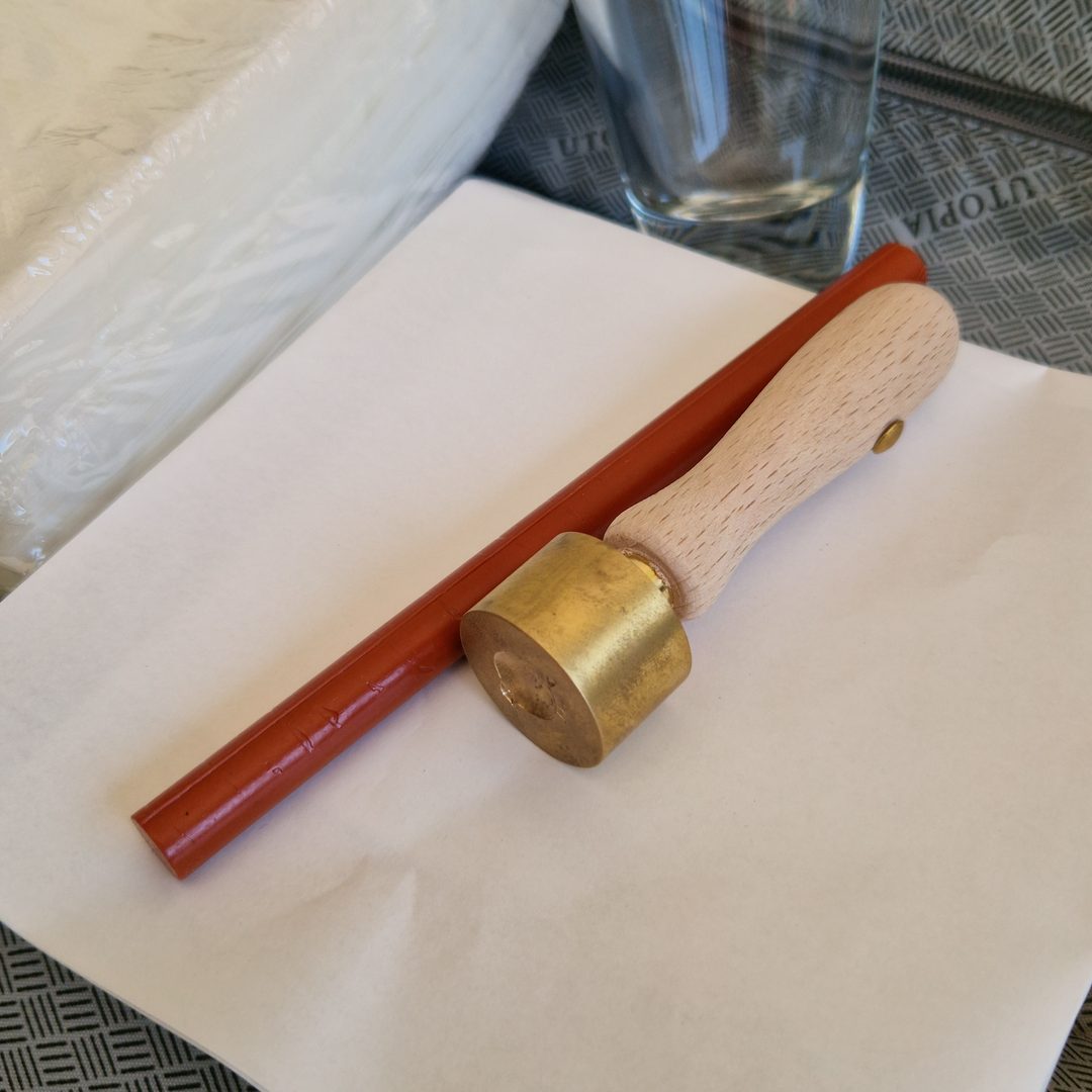 Bâton de cire terracotta et tampon du sceau posés sur le papier, dans la valise d'un confiseur artisanal de La Réunion — La Caille Blanche